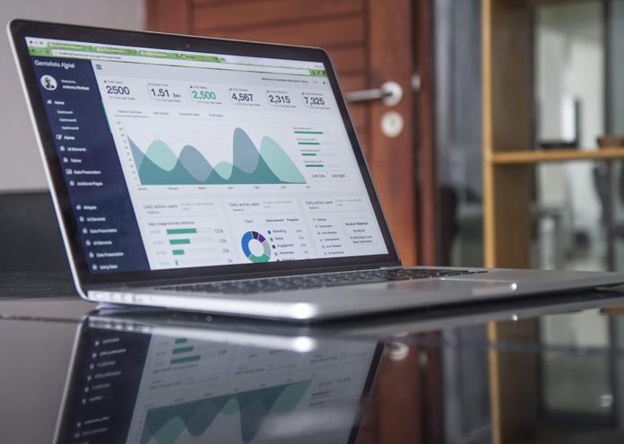 laptop computer with financial data on glass-top table