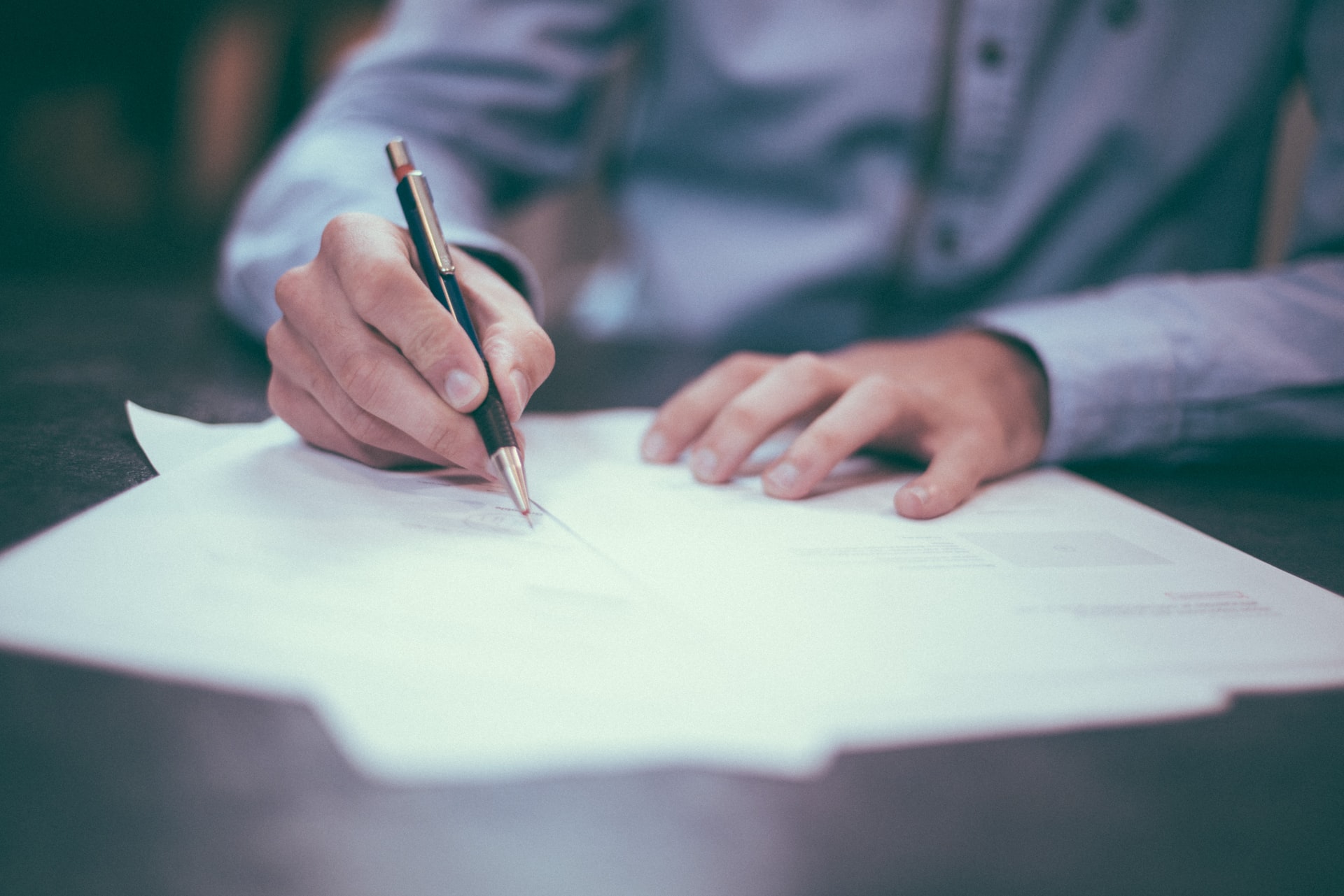 man writing on financial papers