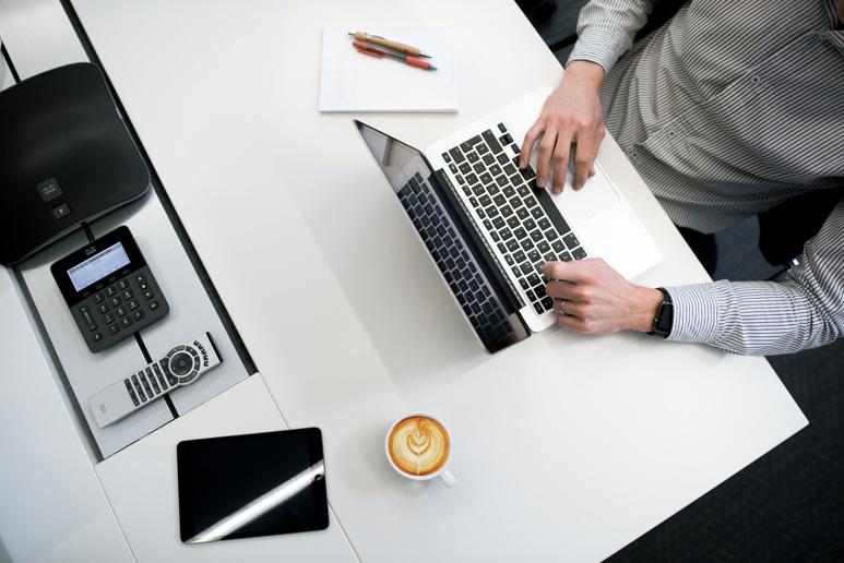 NetSuite Manufacturing Execution person using laptop on white wooden table