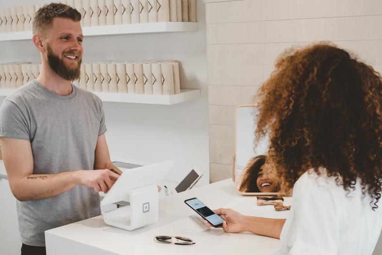 NetSuite SuiteBilling man in grey crew-neck t-shirt smiling to woman on counter