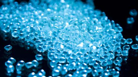 glowing blue polymer pellets on a black background