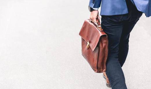 person walking holding brown leather bag