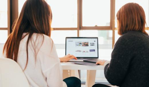 two women talking while looking at laptop computer