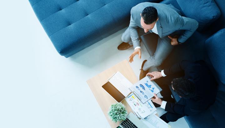 two business people sitting on a couch looking over data